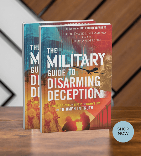 Two copies of The Military Guide to Disarming Deception book on a wooden table.