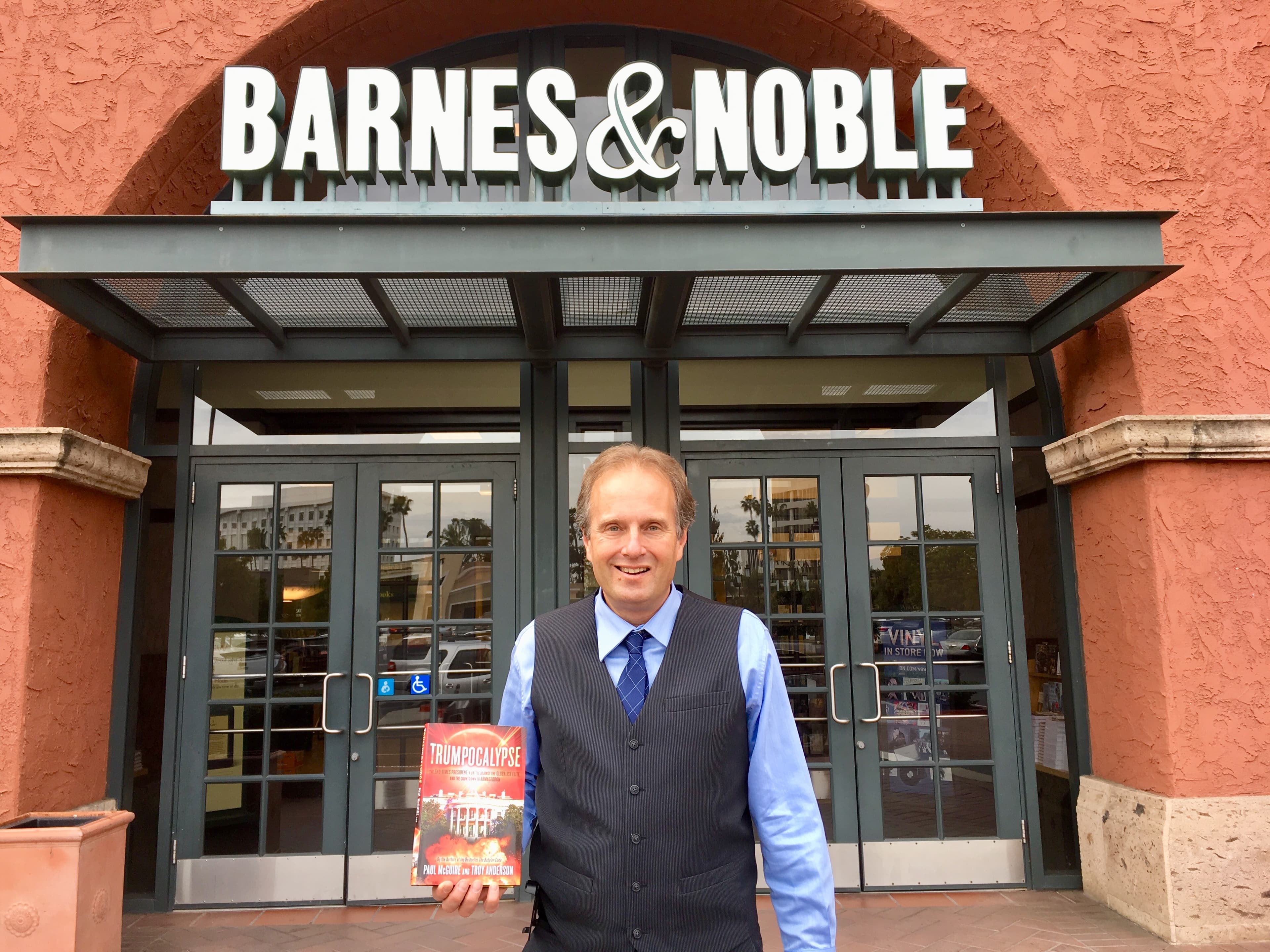 一名男子在 Barnes & Noble 書店前手持《Trumpocalypse》一書微笑合影。
